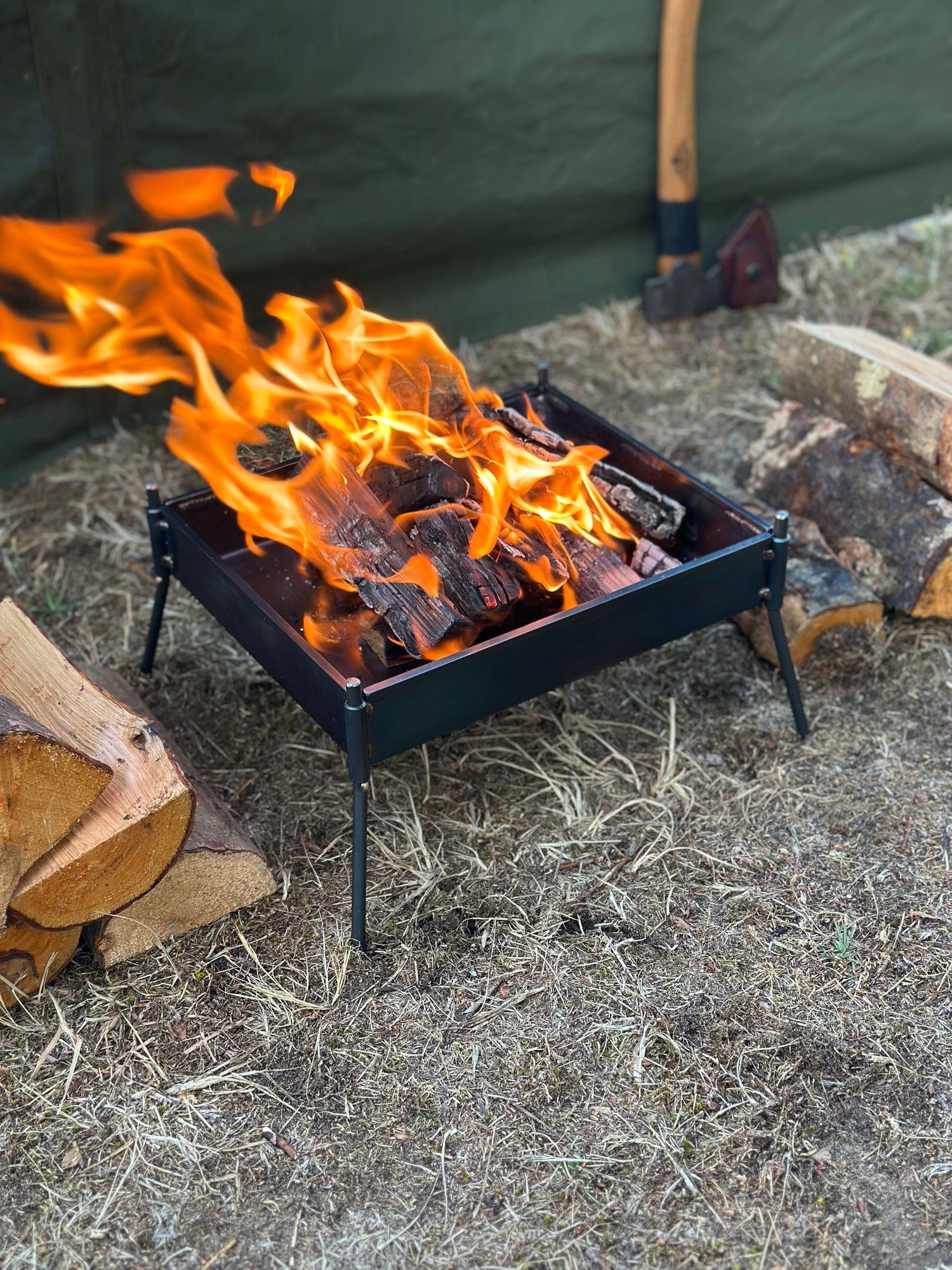 Small campfire with flames burning in a metal fire pit outdoors.