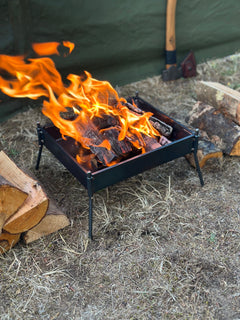 Small campfire with flames burning in a metal fire pit outdoors.