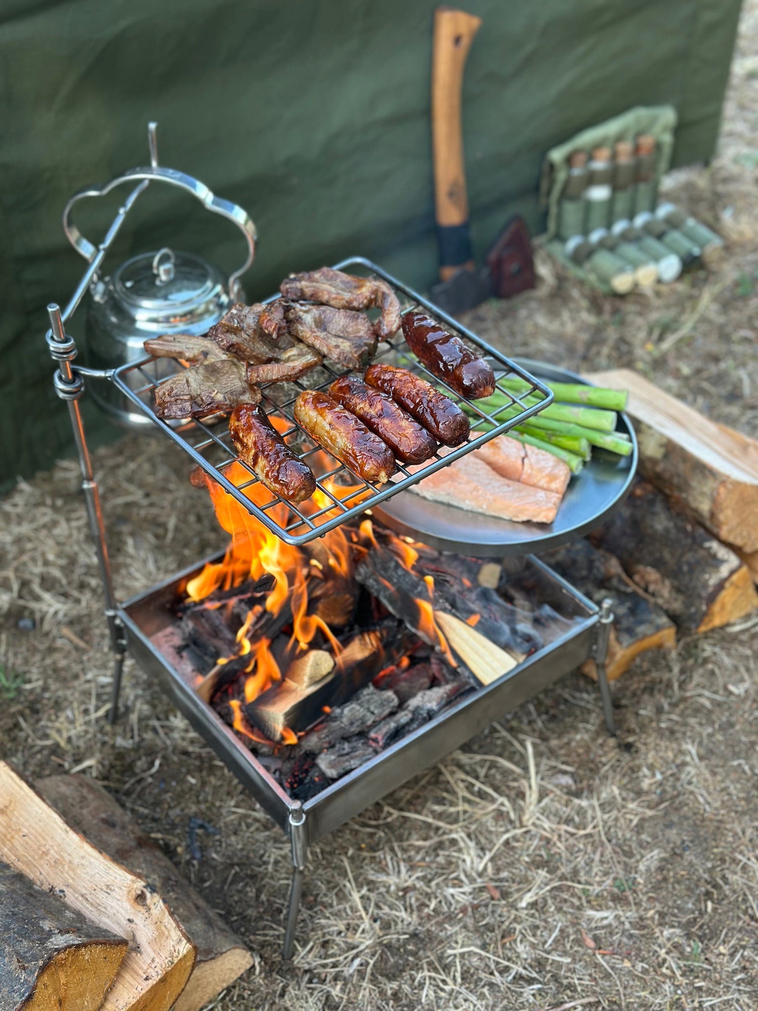 Outdoor cooking setup with meats on a grill over a fire pit.